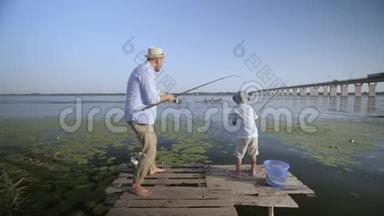 逗乐的父亲和儿子fishermÐ°欢快的，欢快的小男孩戴着草帽在码头的码头上钓鱼